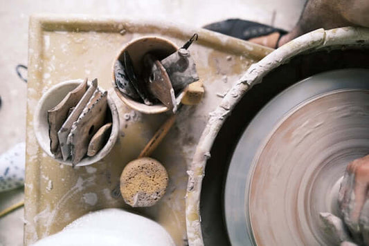 overhead view of pottery tools and a spinning pottery wheel with clay in a creative workspace