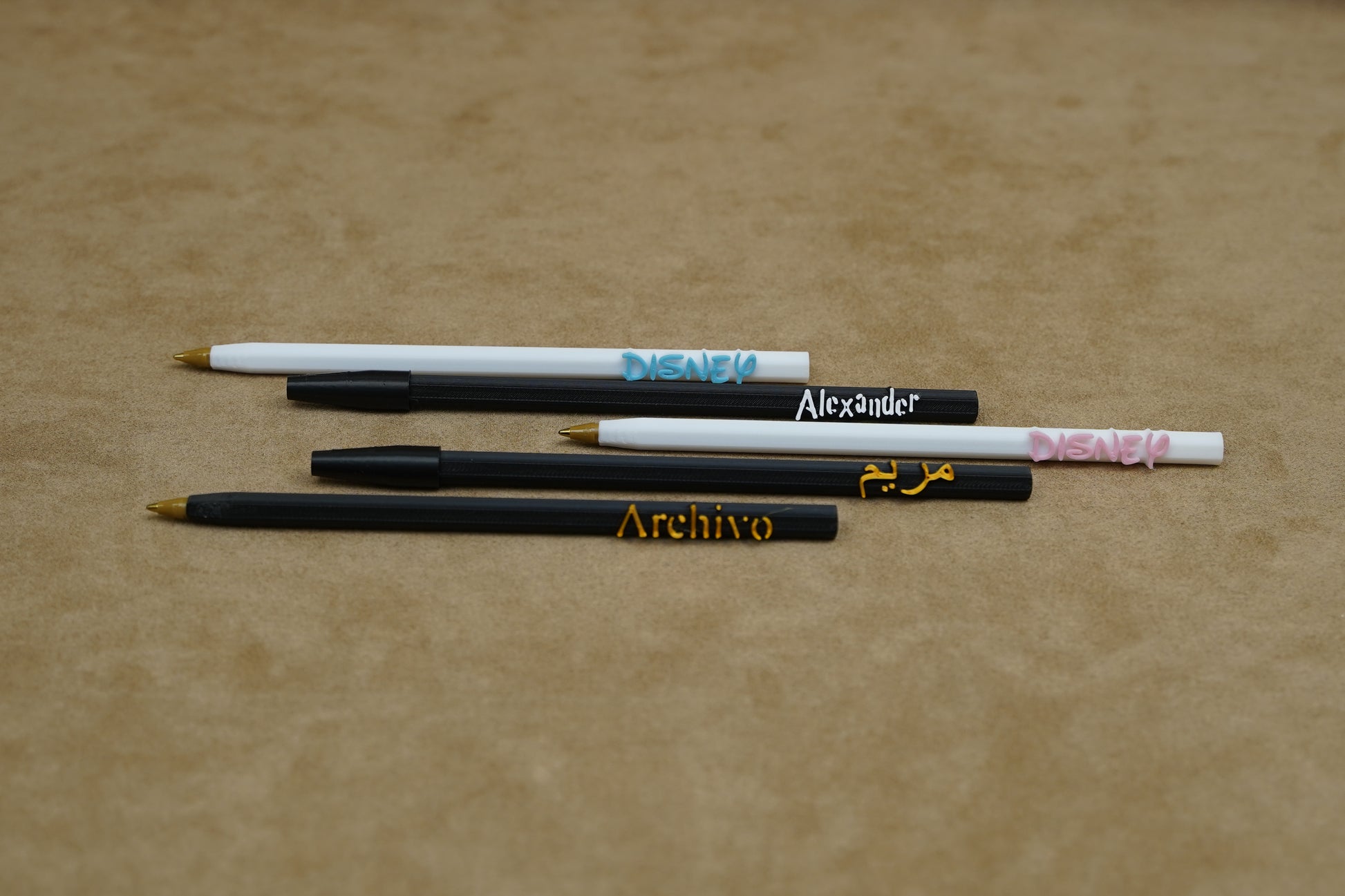 Personalised pens featuring names like Alexander and Archivo on a soft surface, showcasing unique writing experiences.