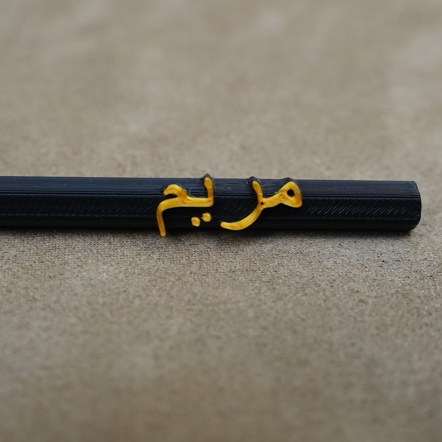 Personalised pen with golden name engraving on a black barrel, set against a soft background.