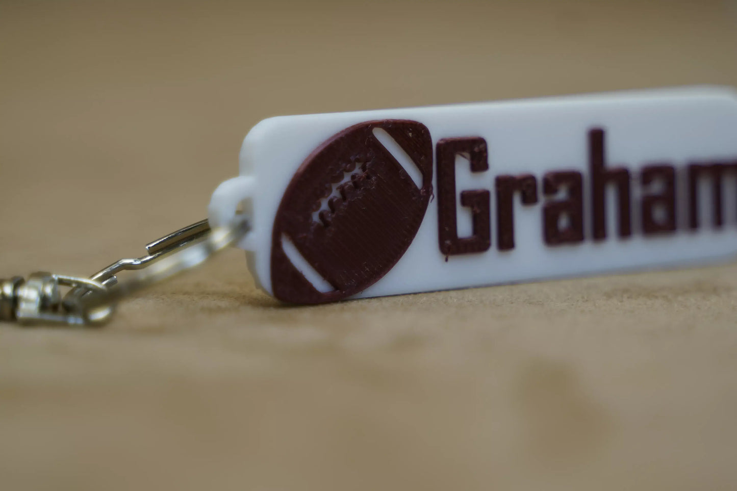 Personalised footy keychain with the name Graham, featuring a football design in brown on a white background.