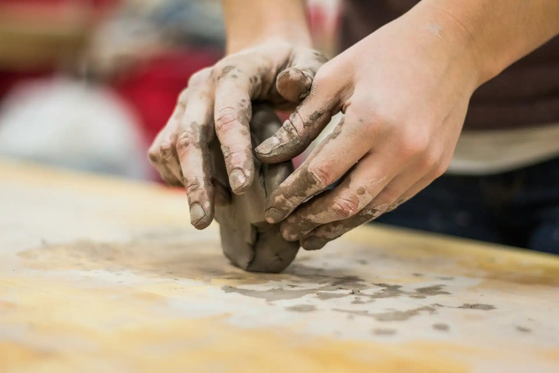 Hands kneading and shaping clay on a work surface